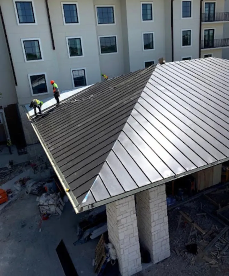 Crew installing standing seam metal roof panels on a commercial project in Thetford